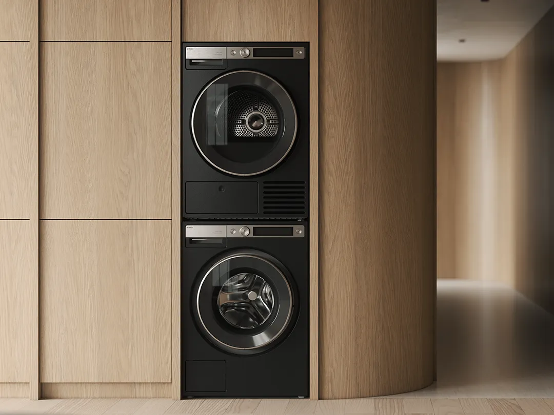 ASKO graphite black washing machine and tumble dryer stacked in integrated wood cabinetry ASKO graphite black washing machine and tumble dryer stacked in integrated wood cabinetry
